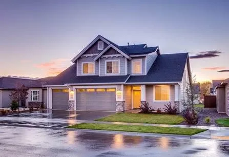 Large house with a garage and a driveway on a rainy day.